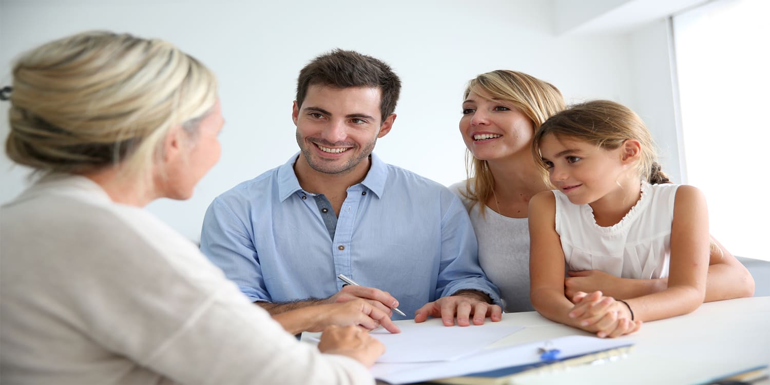 Realtor consulting with clients at desk.